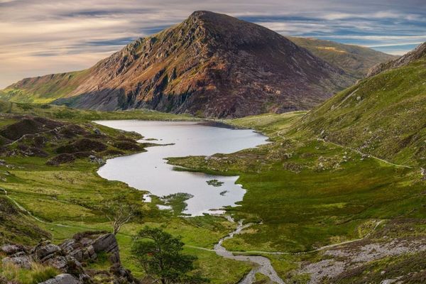A lake in a green valley below a mountain in North Wales